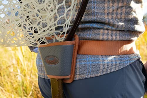 Person wearing a fishing net holder on a belt in outdoor setting.
